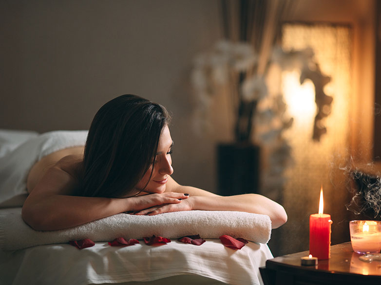 woman laying on massage bed next to candle surprising benefits of massage