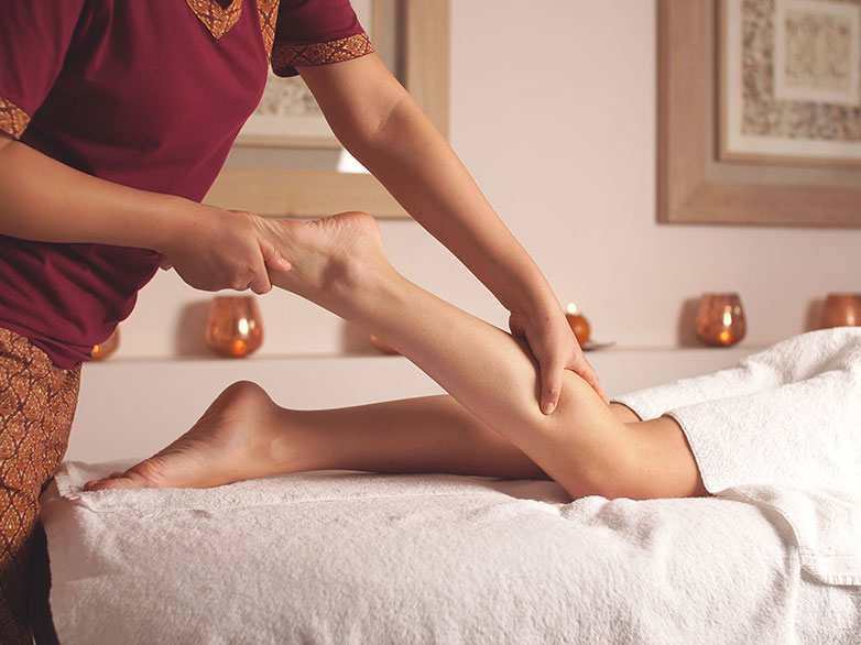 person massaging a womans leg on a massage table