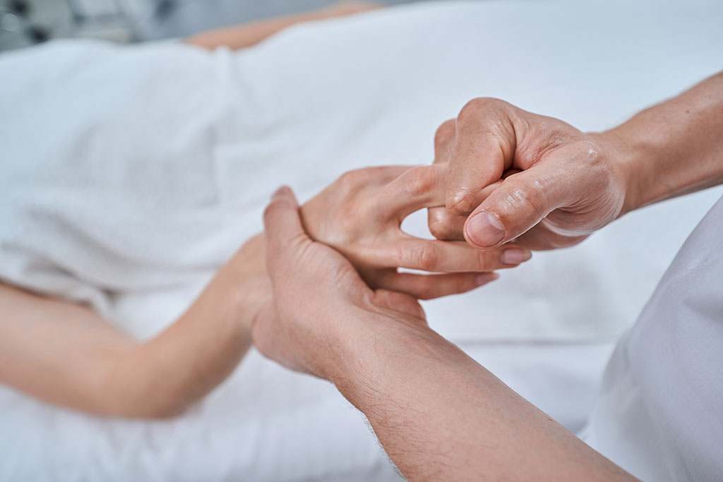 Cropped photo of a female patient having her fingers massaged by an experienced male reflexologist
