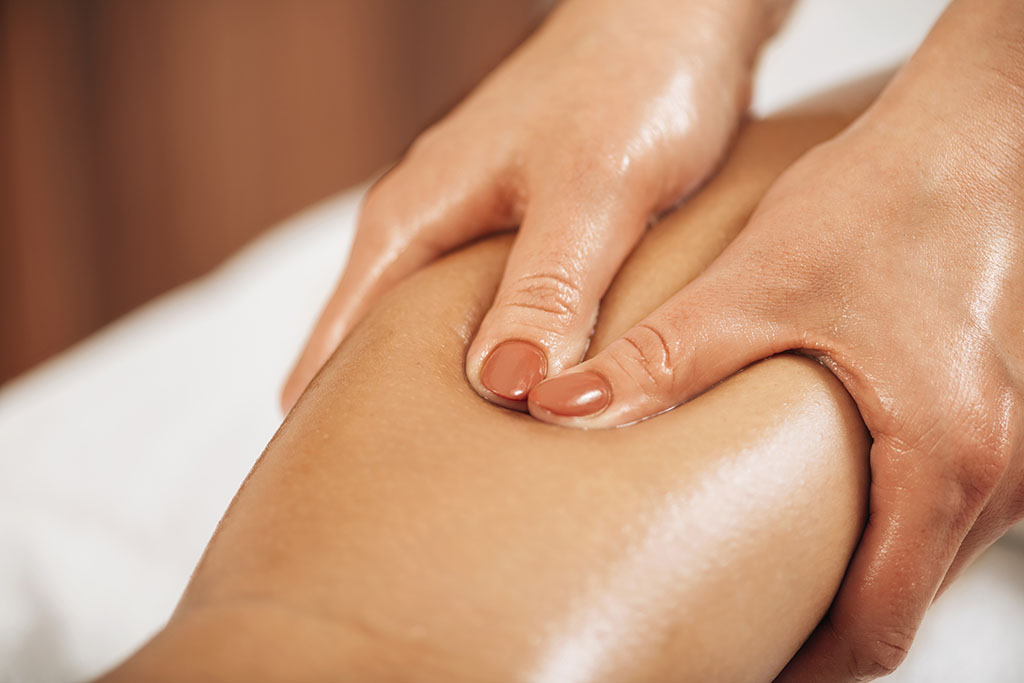 Lymphatic drainage massage. Hands of a masseuse massaging leg of a female client chicago lymphatic massage